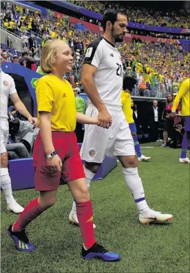  ?? PHOTO: GETTY IMAGES ?? Eight-year-old CHB schoolgirl Sophie Heywood holds the hand of Costa Rica striker Marco Urena as they walk on to the pitch before the match against Brazil in St Petersburg.