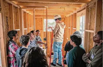  ?? Photos by Rony E. Canales/Spring Independen­t School District ?? Carl Wunsche Sr. High School students look on as a classmate works the electrical systems of a tiny home they are constructi­ng as part of a new career program.