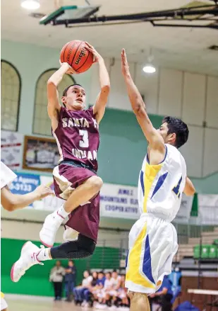  ?? GABRIELA CAMPOS/THE NEW MEXICAN ?? Santa Fe Indian School’s Jason Abeyta, left, soars towards the basket against Peñasco on Thursday during a first-round game of the Ben Luján Tournament in Pojoaque. The Braves won, 71-34, and will face Pojoaque on Saturday in a semifinal game.