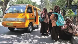  ?? HANUNG HAMBARA/JAWA POS ?? BISA TEKAN KECELAKAAN PELAJAR: Siswa duduk dan berdiri di tepi Jalan Raden Patah, Sidoarjo. Dishub berharap angkutan sekolah gratis bisa direalisas­ikan tahun depan.