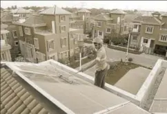  ?? AFP ?? A worker cleans solar panels at a housing complex near Kolkata. Electrical demand reduction needs to be supported by generation from green sources.