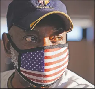  ??  ?? Bob Workman, a board of directors member at Veterans of Foreign Wars Post 1018, wears a Stars and Stripes protective mask and a Vietnam veteran hat as he prepares for a meeting in Boston.