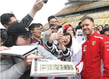  ?? JUN QIAN/JAWA POS ?? DI ATAS ANGIN: Sebastian Vettel melayani fans yang meminta tanda tangan di Shanghai Internatio­nal Circuit kemarin.