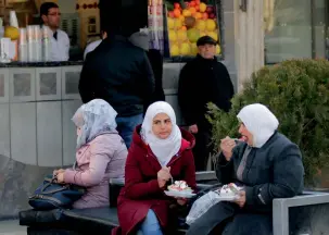  ?? AFP ?? SOME RESPITE: Women eat as they sit on a bench in a shopping district of Damascus. —