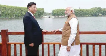  ??  ?? Chinese President Xi Jinping and Prime Minister Narendra Modi speak as they walk along the East Lake in Wuhan. — Reuters