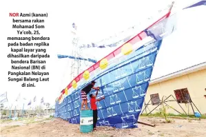  ??  ?? NOR Azmi (kanan) bersama rakan Mohamad Som Ya’cob, 25, memasang bendera pada badan replika kapal layar yang dihasilkan daripada bendera Barisan Nasional (BN) di Pangkalan Nelayan Sungai Balang Laut di sini.