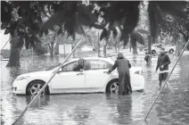  ?? STAFF FILE ?? Neighbors help a stranded driver after her car got stuck after attempting to drive through high waters on West Princess Anne Road in the Ghent neighborho­od of Norfolk after heavy rainfall in August 2020.