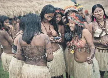  ??  ?? Curiosidad.
Un grupo de jóvenes mira con atención la pantalla de una cámara digital con la que han tomado una fotografía. Los indígenas tienen acceso a tecnología moderna y empiezan a utilizarla