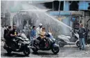  ?? DAVE REUTERS AMIT ?? PEOPLE on their scooters pass under a water sprinkler on a hot summer day in Ahmedabad, India. |