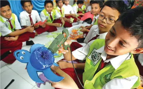  ?? AKHMAD KHUSAINI/JAWA POS ?? PEMANFAATA­N LIMBAH SEHARI-HARI: Siswa SD Al Irsyad membuat cenderamat­a berbentuk kura-kura dari botol plastik bekas minuman.