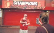  ?? AFP ?? A Liverpool fan, holding his baby, poses for a photo outside Anfield to celebrate the club winning the league title.