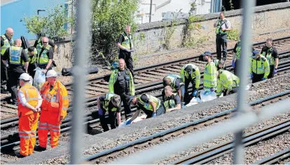  ?? Picture: ROB PINNEY/LNP ?? Police and rail staff gather evidence at the scene yesterday after the young men were hit by a freight train