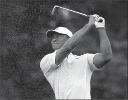  ?? The Associated Press ?? MYSTERY MAN: Tiger Woods hits from the first fairway Tuesday during a practice round for the PGA Championsh­ip at Bellerive Country Club in St. Louis.