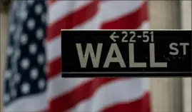  ?? Johannes Eisele/AFP via Getty Images ?? The U.S. flag hangs at the New York Stock Exchange near a street sign marking Wall Street.