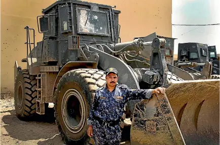  ?? PHOTO: WASHINGTON POST ?? Private Muhsin Harir Abed,40, from Dewaniya, Iraq, stands in front of the wheeled-dozer he shares with Mohammed Kareem Ahmed.