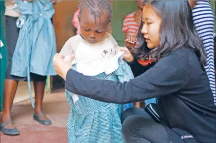  ?? PHOTOS BY FIONA XIAOJUN GUO / FOR CHINA DAILY ?? Yuan Xiaoyi dresses a girl at the Compassion Children Centre in Nairobi.