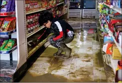  ?? ?? Gaeb Ali, 8, helps clean up his father's mini-market after the evacuation order was lifted in Pajaro on Thursday.