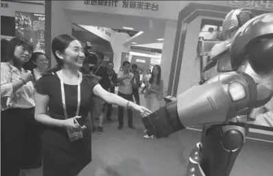  ?? CAO BOYUAN / FOR CHINA DAILY ?? A visitor shakes an AI-powered robot’s hand at the 5th China Beijing Internatio­nal Fair for Trade in Services on May 28.