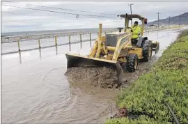  ?? Katie Falkenberg Los Angeles Times ?? A WORKER cleans up a mudslide on Pacific Coast Highway across from Zuma Beach in Malibu as a f lash-f lood warning was in effect on Thursday morning.