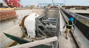  ?? ?? A worker crosses a catwalk above the tunnel boring machine launch shaft at the South Island of the Hampton Roads BridgeTunn­el.