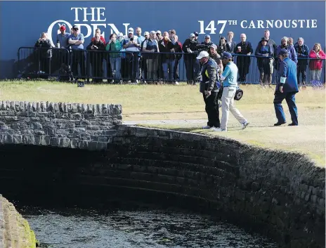  ?? ALASTAIR GRANT/THE ASSOCIATED PRESS ?? Kevin Kisner talks to officials after hitting the ball into the Barry Burn on the 18th hole during second-round play at the British Open in Carnoustie, Scotland on Friday. Despite finishing with a double bogey, the American shares the lead at the midway point.