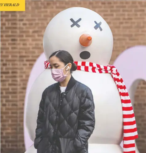  ?? PETER J THOMPSON / POSTMEDIA NEWS ?? A pedestrian walks past a snowman in Toronto on Thursday, as COVID restrictio­ns across Canada are changing how the holidays are observed.