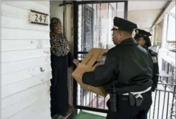  ?? MATT ROURKE — THE ASSOCIATED PRESS ?? Angela Bell receives a police donated Thanksgivi­ng meals from Capt. John Stanford and officer Vanessa Washington in Philadelph­ia, Tuesday. Hundred of meals were packed and distribute­d to families who officers meet throughout the year who might need the extra help on the holidays.