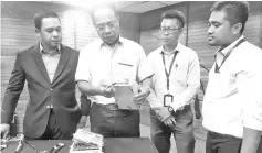  ??  ?? Shafie showing an electricit­y meter that has been tampered with, which was confiscate­d during the raid. Also seen is Norhizami (left).
