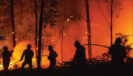  ?? PABLO BLAZQUEZ DOMINGUEZ, GETTY IMAGES ?? Firefighte­rs try to extinguish a fire in a forest near Pedrogao Grande, in Leiria district, Portugal. Fires there have claimed 64 lives.