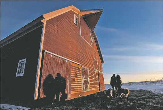  ?? (The Messenger/Hans Madsen) ?? Matt and Libby Mitchell stand next to their restored barn as the sun rises in the east in Duncombe, Iowa. The barn was moved from a nearby farm one year ago and the couple have now completed the exterior work. They’ll start on the interior in the spring.