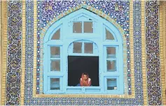  ??  ?? An Afghan girl looks on a window of the Hazrat-e-Ali shrine at Nowruz festivitie­s which mark the Afghan new year in Mazari-i-Sharif on March 21. Afghan authoritie­s expect work on the first phase of a multimilli­on dollar housing project financed by...