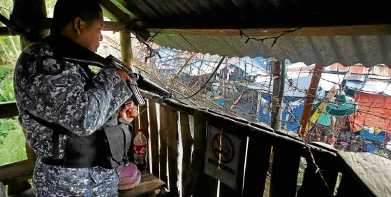  ?? —REUTERS ?? A prison guard watches over the compound of the North Cotabato District Jail in Kidapawan City following the escape of more than 150 inmates on Wednesday morning.