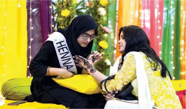  ?? Agence France-presse ?? ↑ A woman gets her hand decorated with henna at a temporary stall inside a mall ahead of Eid Al Fitr in Islamabad on Sunday.