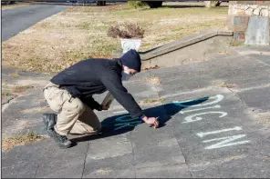  ??  ?? A.B. Stewart, program director of Full Circle FarmCorps, chalks the slogan “Dig in for food” in front of St. Joseph Center.