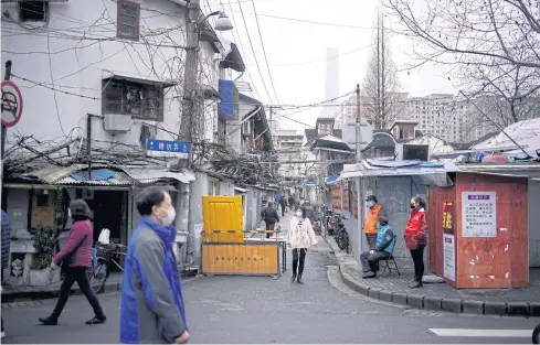  ??  ?? BETTER SAFE THAN SORRY: People wear face masks at a residentia­l community following the Covid-19 outbreak in Shanghai, China on Friday. While infections continue to climb around the world, in mainland China the number of new cases is falling.