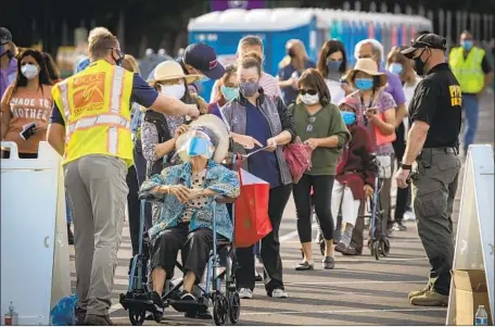  ?? Allen J. Schaben Los Angeles Times ?? PEOPLE line up in the Toy Story parking lot at Disneyland on Wednesday to get the COVID-19 vaccine as Orange County opened five mass-vaccinatio­n centers. As the pool of those eligible for a vaccine grows, so does the confusion over seemingly simple details.