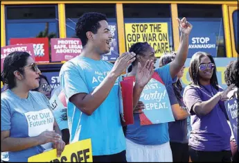  ?? STEVE MARCUS ?? Quentin Savwoir, second from left, deputy field director for Make It Work Nevada, and others applaud a speaker during a “Hop on the Progress Bus” news conference Sept. 19.