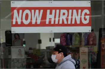  ?? PHOTO/JEFF CHIU
AP FILE ?? In this May 7 file photo, a man wearing a mask walks under a Now Hiring sign at a CVS Pharmacy during the coronaviru­s outbreak in San Francisco.