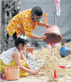  ?? VARUTH HIRUNYATHE­B ?? Youngsters get creative as they try to sculpt sand figures during a Songkran celebratio­n at Wat Siripong Thammanimi­t in Bang Khen.