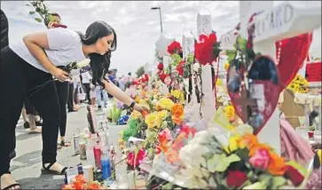  ?? Mario Tama Getty Images ?? A WOMAN places flowers at a memorial honoring victims outside a Walmart in El Paso, where a shooting left 22 people dead on Aug. 3. The next day, nine other people were killed in a shooting in Dayton, Ohio.