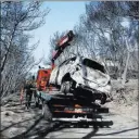  ?? Thanassis Stavrakis ?? The Associated Press A worker transports a burnt car after a wildfire Friday in Neos Voutzas, Greece.