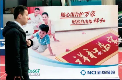  ?? A QING / FOR CHINA DAILY ?? A man passes by the billboard of New China Life Insurance Co at an insurance fair in Beijing.
