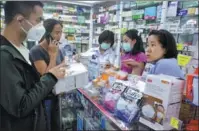  ?? CHEN PENGPENG / FOR CHINA DAILY ?? Volunteers Guo Zhaowei (second from left) and Li Kun (left), from Guizhou province, purchase masks at a pharmacy in Thailand on Jan 29.