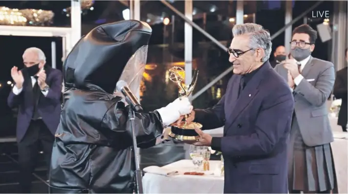  ??  ?? Una postal irrepetibl­e: Eugene Levy, protagonis­ta de la comedia canadiense Schitt’s Creek, recibe el premio con las medidas sanitarias obligadas por la pandemia.