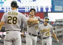  ?? Duane Burleson / Getty Images ?? Matt Olson greets Chad Pinder (18) and Matt Chapman (26) after they scored on Stephen Piscotty’s seventh-inning double.