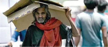  ?? Agence France-presse ?? ↑
A man takes shelter under a cardboard sheet from the scorching sun on a hot summer afternoon in New Delhi, recently.