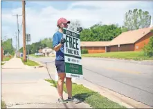  ?? [SARAH PHIPPS/ THE OKLAHOMAN] ?? Candice Hillenbran­d, director of mission engagement at St. Luke's United Methodist Church, holds a sign advertisin­g free produce and restaurant meals on Tuesday at John F. Kennedy Park, 1824 NE 16.