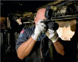  ?? TOM LEE/STUFF ?? Kevin Holmes takes photos of the burnt out house.