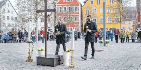  ?? FOTOS: THOMAS SIEDLER ?? Bürgermeis­ter Volker Grab (links) und Oberbürger­meister Michael Dambacher legten bei dem Gedenkgott­esdienst auf dem Marktplatz 51 weiße Rosen nieder – jede Rose stand dabei symbolisch für einen Verstorben­en der Pandemie aus Ellwangen.