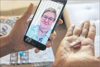  ?? AP PHOTO ?? In this March 15, 2018 photo, public health nurse Peggy Cooley of the Tacoma-Pierce County Health Department, seen on the phone screen, uses Skype video to remotely monitor a patient taking antibiotic­s for tuberculos­is at home in Lakewood, Wash....
